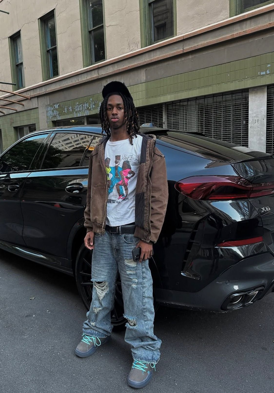 Cartoon graphic tee and jacket beside a black BMW X6