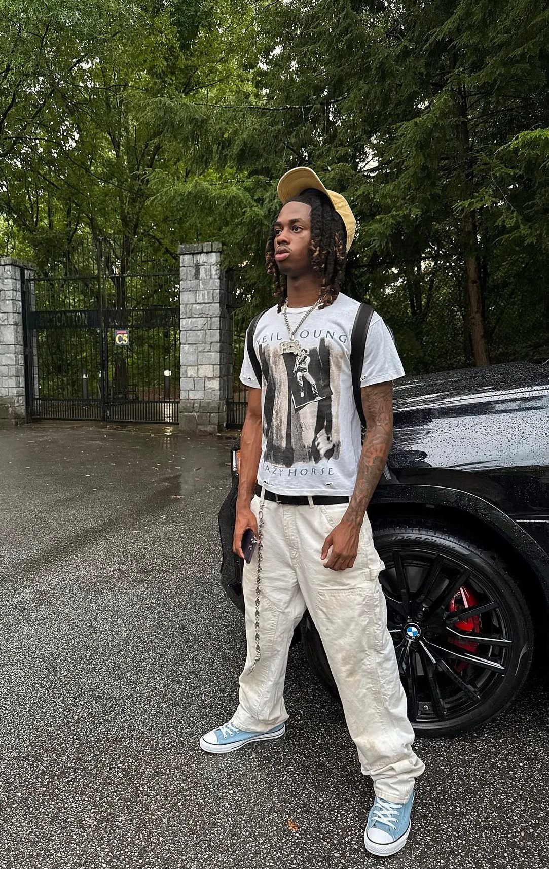 Vintage band tee and cargos beside a BMW