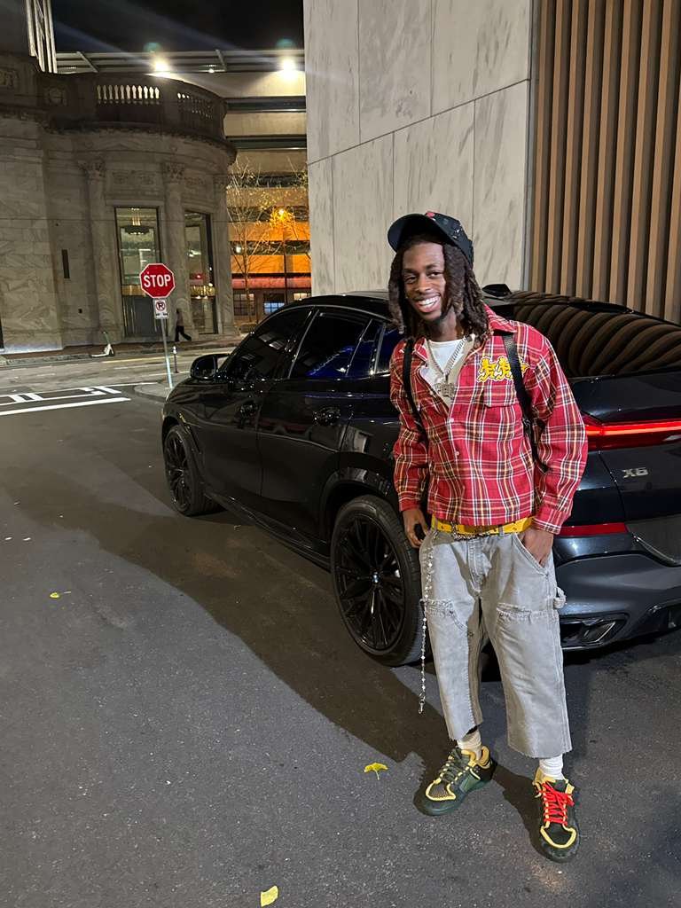 Knowledge Chambers smiling in a red plaid shirt on a city street at night