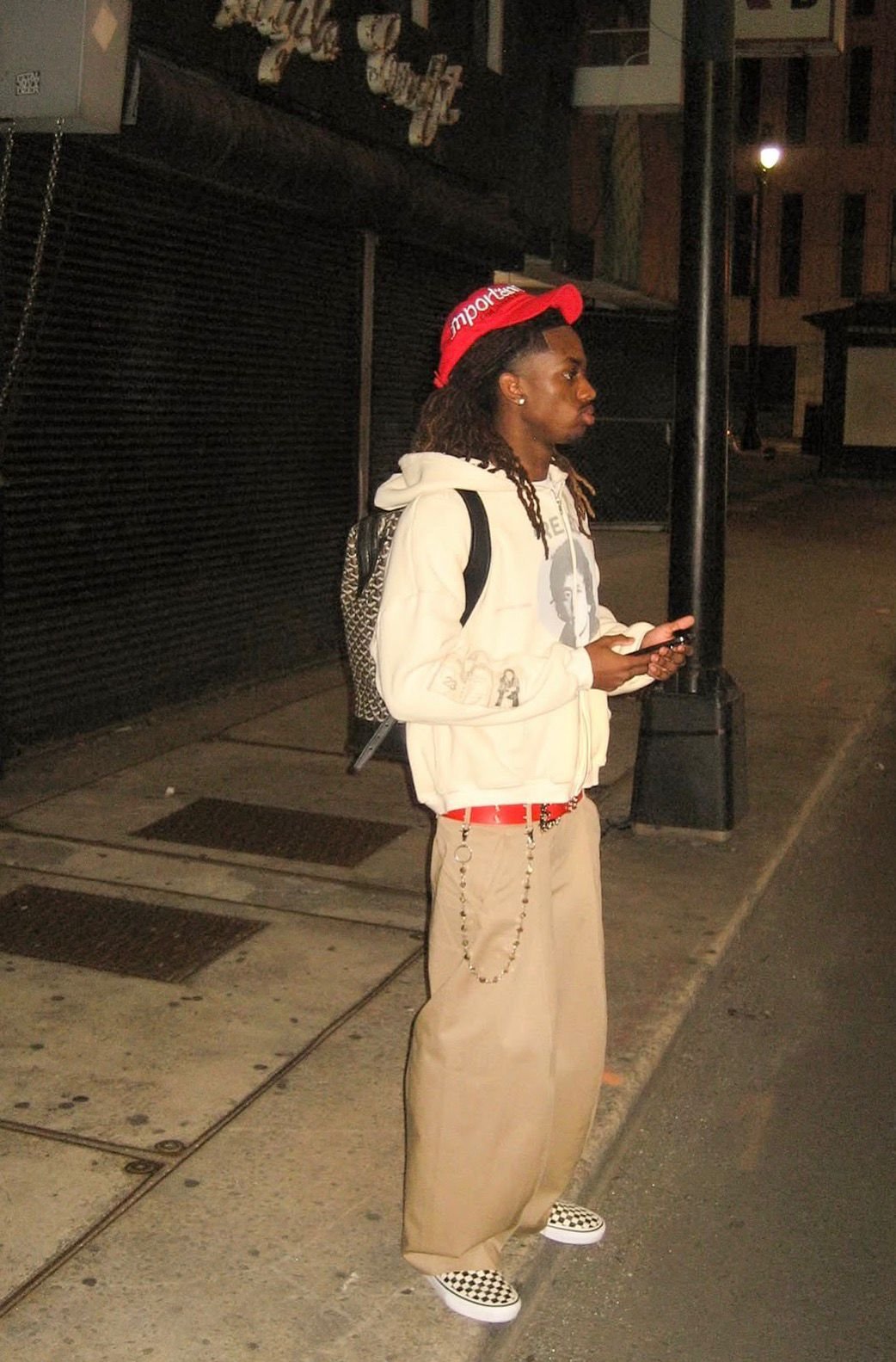 Red important cap, hoodie and wide-leg trousers at night