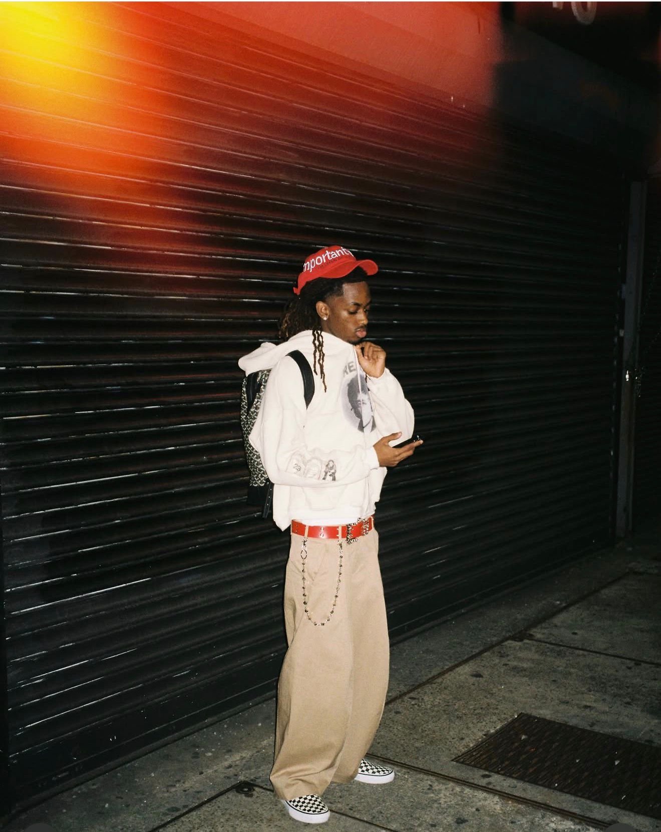 Red cap and graphic hoodie against a shop shutter